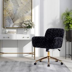 a black chair sitting on top of a wooden floor next to a white table and potted plant