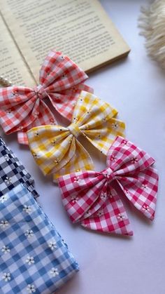 four different colored bows sitting on top of a white table next to an open book