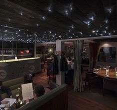 people sitting at tables in a restaurant with lights hanging from the ceiling