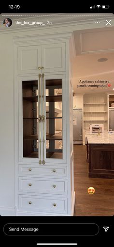 a large white cabinet with glass doors in a kitchen next to an oven and sink