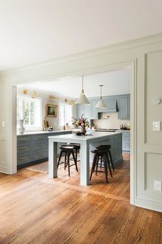 an open kitchen with blue cabinets and stools on the island in front of it