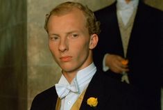 a man in a tuxedo with a yellow rose on his lapel