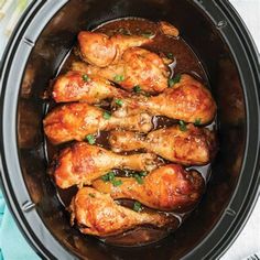 chicken wings in a slow cooker with brown sauce and parsley on the side