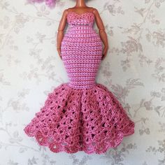 the doll is wearing a pink crocheted dress