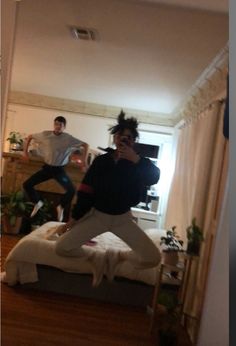 two people are dancing in the living room while another person is taking a selfie