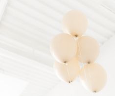 several white balloons are suspended from the ceiling in a room with white walls and ceilings