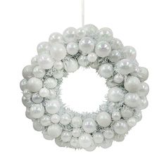 a white christmas wreath hanging from the ceiling with ornaments around it and balls on top