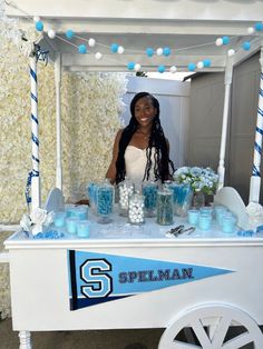 a woman standing behind a table with blue and white decorations