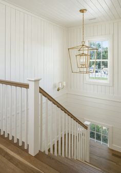 a white house with wood flooring and wooden handrails that lead to the second floor