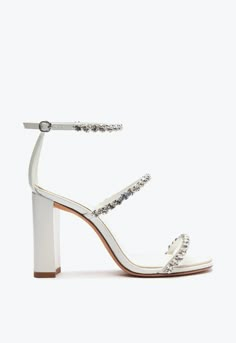 a woman's white high heeled sandal with crystal embellishments