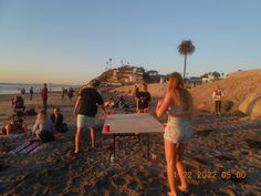 a group of people standing on top of a sandy beach