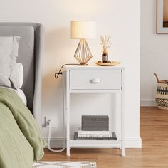 a white nightstand with books on it next to a bed