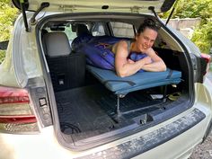 a man laying in the back of a car on top of a blue seat cushion