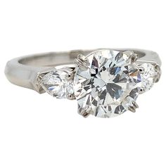 a three stone diamond ring with two diamonds on the band and an oval shaped center