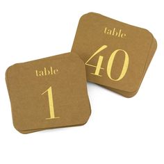 two brown coasters with gold numbers and the words table 40 on them are sitting next to each other