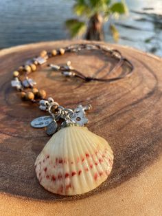 This necklace has been handcrafted on a beautiful espresso leather. This scallop seashell is from the shores of the FL Panhandle. It has been adorned in petite swarovski crystals and accents. The shell has been coated with a resin and charms have also been added. The charms are oxidized silver metal which gives this necklace a vintage appeal. (Charms include a cross, large and small ovals , and a flower). The necklace is double strand and has jasper gemstones, silver metal accents, and petite foil glass beads.   The length of the necklace is a total of 28 inches in the neck area (14 each. side). The shell is 2 inches wide. This is the perfect necklace to slip on and off over the head. No clasps to fasten.  The necklace ties at the neck area and the tassel ends have petite beads and silver Bohemian Brown Shell As Gift, Handmade Brown Shell-shaped Necklace, Handmade Brown Shell-shaped Jewelry, Handmade Brown Shell Necklace, Handmade Brown Shell As Gift, Handmade Brown Shell As A Gift, Bohemian Brown Shell Jewelry, Handmade Brown Shell For Gift, Handmade Brown Shell Gift