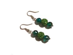 Prepare to elevate your style with these enchanting green dangle earrings that are destined to steal the spotlight. Imagine pairing them with your favorite outfit and watch as heads turn in awe. Crafted with meticulous detail, these one-of-a-kind earrings feature mesmerizing green lampwork and emerald green beads, suspended gracefully from sterling silver French ear wire hooks. Picture yourself donning these statement earrings, each pair measuring a chic 2 ½ inches in length. Unleash your inner Green Beaded Emerald Jewelry, Green Beaded Dangling Earrings For Party, Nickel-free Green Beaded Earrings For Parties, Trendy Green Beaded Dangle Earrings, Elegant Green Beaded Drop Earrings, Elegant Green Beaded Crystal Earrings, Dark Green Beaded Jewelry Gift, Dark Green Beaded Jewelry For Gift, Trendy Green Beaded Drop Earrings