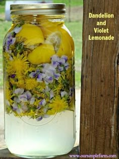 a mason jar filled with lemons and purple flowers next to a wooden fence post