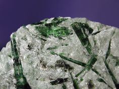 some green and white crystals on a purple surface with blue sky in the back ground