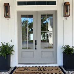 a front door with two planters on the side and a welcome mat in front