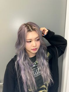 a woman with long grey hair standing next to a wall