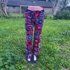 a pair of colorful pants sitting on top of a lush green grass covered field in front of a house