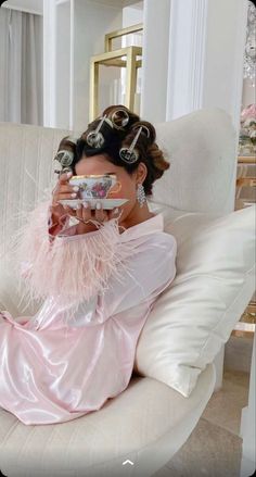 a woman sitting on top of a white couch wearing a pink dress and headpiece