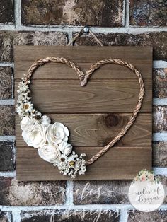 a wooden heart with flowers hanging on a brick wall