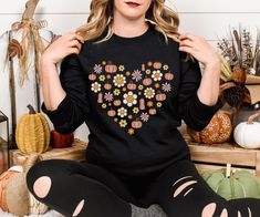 "Embrace the cozy charm of autumn with our Retro Fall Season Sweatshirt, featuring a beautifully crafted heart of autumn design and delicate autumn flowers--perfect for adding a touch of nostalgia to your fall wardrobe." Are you looking for (Retro Season Sweatshirt)? We got you! ✅ ABOUT OUR (Retro Fall Season Sweatshirt) Crewneck ▸These garments are made from polyester and cotton.  ▸The collar is ribbed knit, so it retains its shape even after washing.  ▸ There are no itchy side seams on these s Long Sleeve Sweatshirt For Fall Gift, Fall Long Sleeve Top With Heart Graphic, Crew Neck Sweater As Fall Gift, Crew Neck Sweater For Fall - Great As Gift, Long Sleeve Heart Graphic Sweater For Fall, Retro Heart, Flower Sweatshirt, Autumn Design, Autumn Flowers