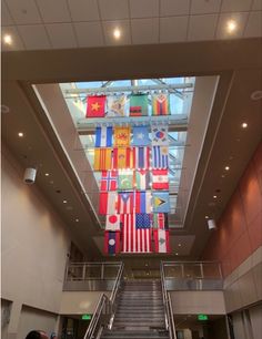 an escalator with flags hanging from the ceiling