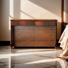 a bed sitting next to a wooden dresser in a room with white walls and flooring