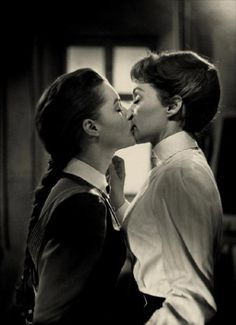 two women are kissing each other in black and white