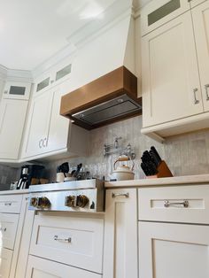 a stove top oven sitting inside of a kitchen next to white cupboards and drawers