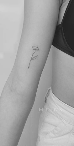 a black and white photo of a woman's arm with a flower tattoo on it