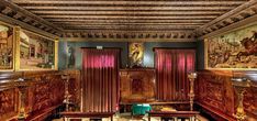 an ornately decorated room with wooden paneling and paintings on the walls, along with tables and chairs