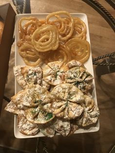 an assortment of pastries on a plate with some onion rings in the middle and other food items around it