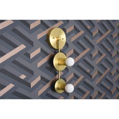 two white and gold knobs are on the wall next to a black and gray geometric pattern