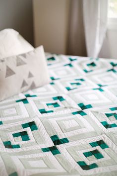 a bed with a green and white quilt on it