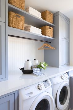 a washer and dryer in a laundry room with baskets on the shelves above