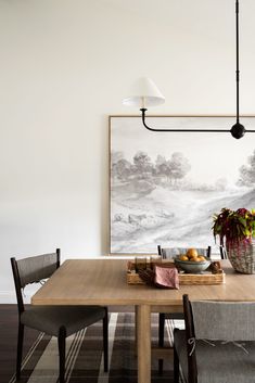 a dining room table with two chairs and a painting on the wall