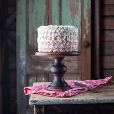 a white and pink cake sitting on top of a wooden table next to an old door