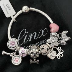 a bracelet with charms on it sitting on a black cloth covered table next to a name tag