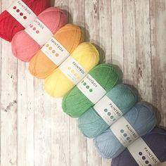 four skeins of yarn sitting on top of a white wooden floor next to each other