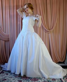 a woman in a white wedding dress posing for the camera with her hand on her head