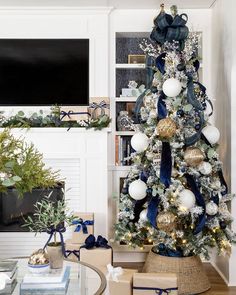 a decorated christmas tree in a living room with blue and white ornaments on the top