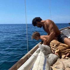 a shirtless man sitting on top of a boat next to an object in the water