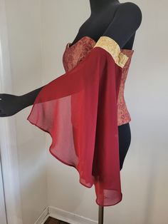 a mannequin wearing a red and gold top with sheer fabric on it's shoulders