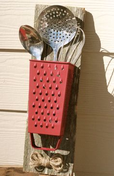 a red utensil holder with two spoons hanging from it's side