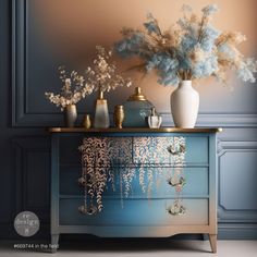 vases and flowers sit on top of a blue dresser in a room with gold trim