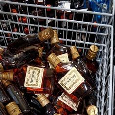 a basket filled with lots of bottles of liquor sitting on top of a floor next to each other